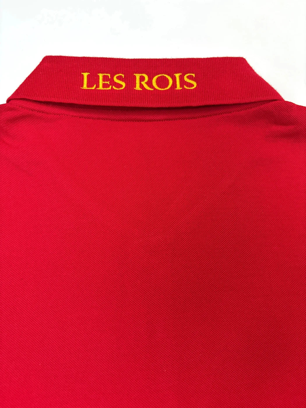 Close-up of gold LES ROIS embroidery on the Rouge Royale polo collar